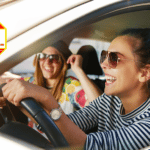 young woman driving car laughing with female friend in passenger seat